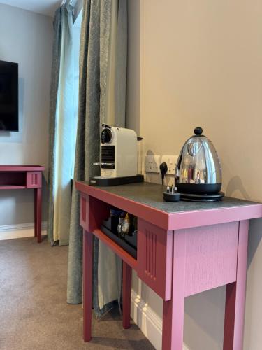 a pink table in a room with a microwave on it at Poets House in Ely