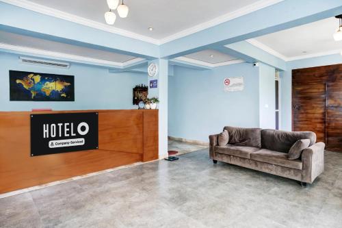 a couch in a lobby with a hotel sign on the wall at Super Hotel O Porvorim in Goa