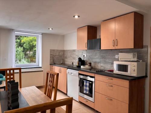 a kitchen with wooden cabinets and a table and a microwave at Appartement tout confort à Begnécourt Vosges endroit calme idéal famille in Begnécourt