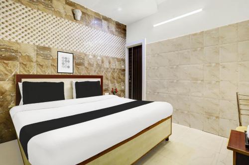 a bedroom with a king sized bed and a stone wall at Hotel O Jammu Near Ragunath Bazaar Formerly GoodWill in Jammu