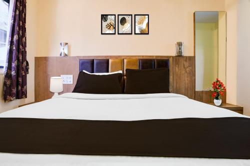 a bedroom with a large bed with a wooden headboard at Hotel O Main Market Mahabaleshwar in Mahabaleshwar