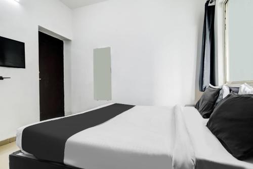 a bedroom with a white bed and a television at Super Hotel O Indraprasth in Indore