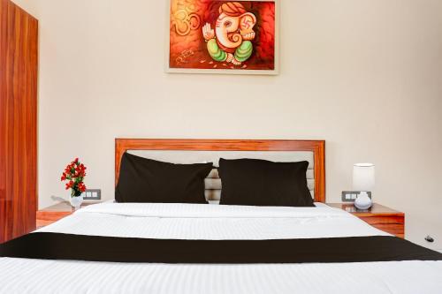 a bedroom with a white bed and a painting on the wall at Collection O Varsoli Uptown formerly Carmello & Othelo Villas in Lonavala