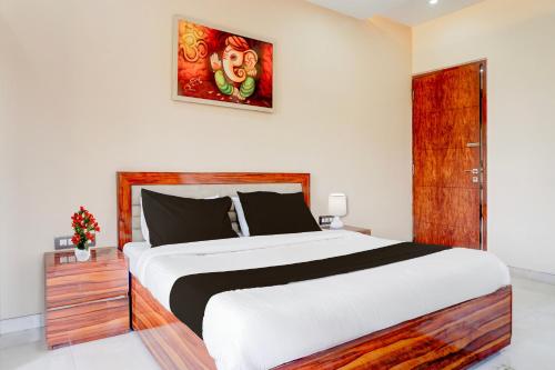 a bedroom with a large white bed and a painting on the wall at Collection O Varsoli Uptown formerly Carmello & Othelo Villas in Lonavala