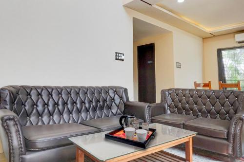 a living room with two leather couches and a table at Collection O Varsoli Uptown formerly Carmello & Othelo Villas in Lonavala