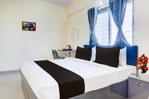 a bedroom with a large bed with blue curtains at Super Collection O Uptown Hinjewadi in Pune