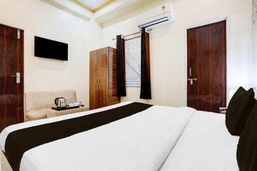a bedroom with a white bed and a chair at Super Hotel O Sankat Mochan Gandhi Nagar in Varanasi