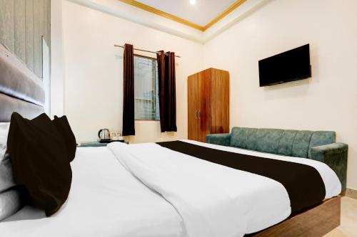 a bedroom with a bed and a couch and a television at Super Hotel O Sankat Mochan Gandhi Nagar in Varanasi