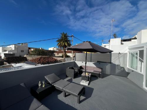 un patio avec un parasol, une table et des chaises dans l'établissement LaCasadelChorro Buenavista del Norte, à Buenavista del Norte