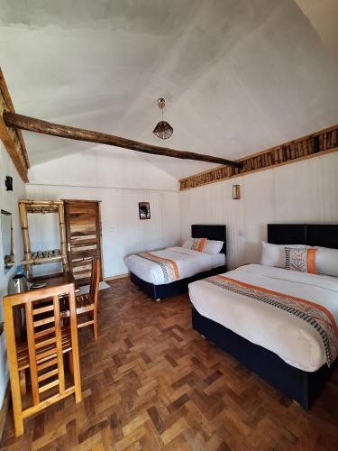 a room with two beds and a desk with a mirror at Ambokili Cottages in Kimana