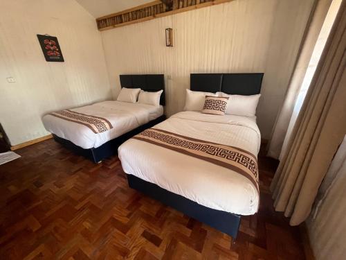 two twin beds in a room with wooden floors at Ambokili Cottages in Kimana