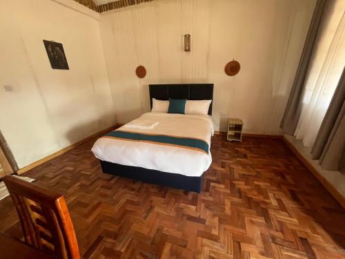 a bedroom with a bed and a wooden floor at Ambokili Cottages in Kimana