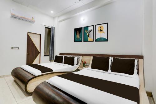 two beds in a white room with black and white at Super Townhouse Khatu Shyam Formerly Hotel Dev Bhumi in Khātu