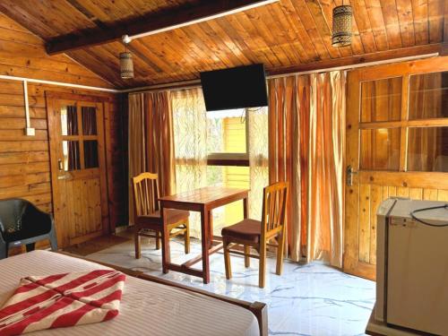 Una habitación con una mesa y sillas y un televisor. en DEER COTTAGES Agonda, en Agonda