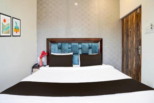 a bedroom with a large bed with a wooden headboard at Super Hotel O Itwari Railway Station Formerly Hotel Prime in Nagpur