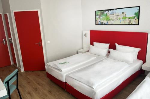 a small room with a bed with a red headboard at Garner Hotel Berlin - Checkpoint Charlie by IHG in Berlin