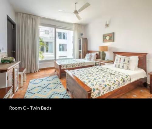 a bedroom with two beds and a desk and a window at 3BHK villa in Candolim, Calangute - IvoryBloom in Candolim