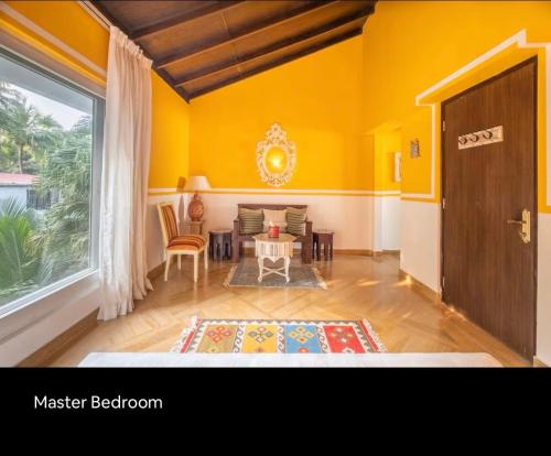 a living room with yellow walls and a table at 3BHK villa in Candolim, Calangute - IvoryBloom in Candolim