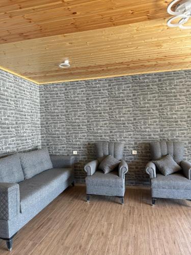 a living room with two couches and a brick wall at Ninama in Mestia