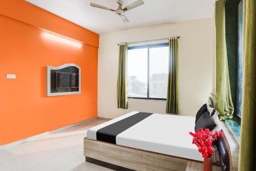 a bedroom with orange walls and a bed and a tv at Super Hotel O Darbhanga Near Khanka Chowk in Darbhanga
