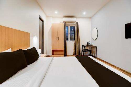 a bedroom with a large white bed and a tv at Super Townhouse Ulsoor Near Halasuru Metro Station in Bengaluru