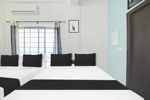 a bedroom with a large white bed with black pillows at Super Collection O Chikmangaluru Near Railway Station in Chikmagalūr