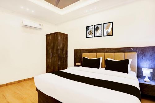 a bedroom with a large white bed with black pillows at Super Townhouse Balua Road Pahadiya in Varanasi