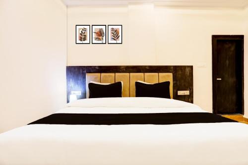 a bedroom with a large white bed with black pillows at Super Townhouse Balua Road Pahadiya in Varanasi
