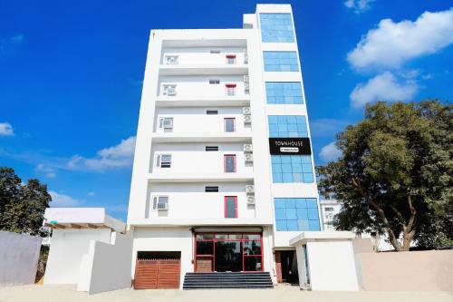 a tall white building with windows on it at Super Townhouse Balua Road Pahadiya in Varanasi