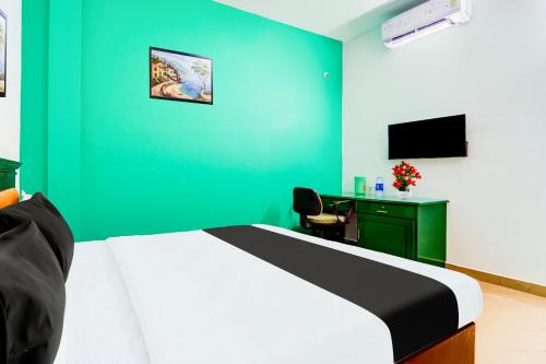a bedroom with a bed and a green wall at Super Hotel O Vennala Near Palarivattom in Ernakulam