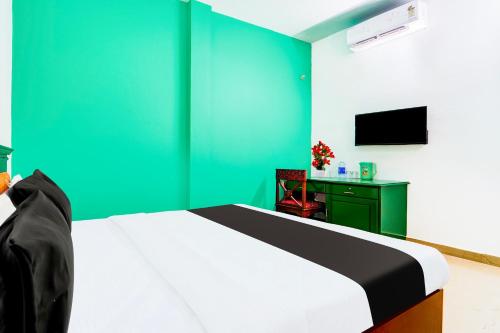 a bedroom with a bed and a green wall at Super Hotel O Vennala Near Palarivattom in Ernakulam