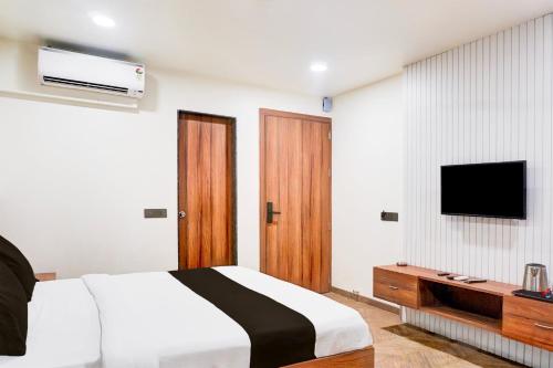 a bedroom with a bed and a tv on the wall at Super Townhouse Oak Viman Nagar formerly Kuber Inn in Pune
