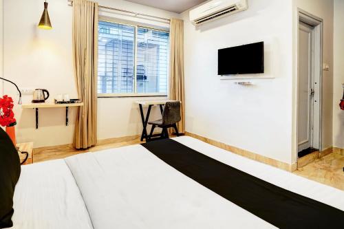 ein Hotelzimmer mit einem Bett und einem Fernseher in der Unterkunft Super Hotel O Katol Road Friends Colony in Nagpur
