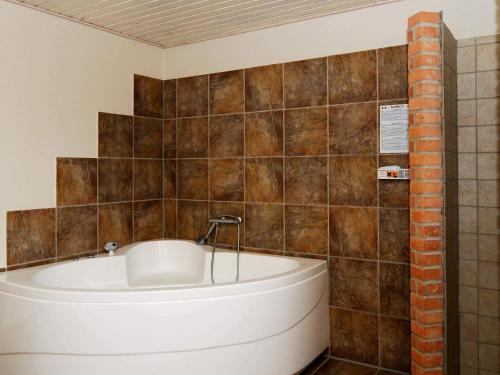 a bath tub in a bathroom with brown tiles at 6 person holiday home in Lemvig-By Traum in Ferring