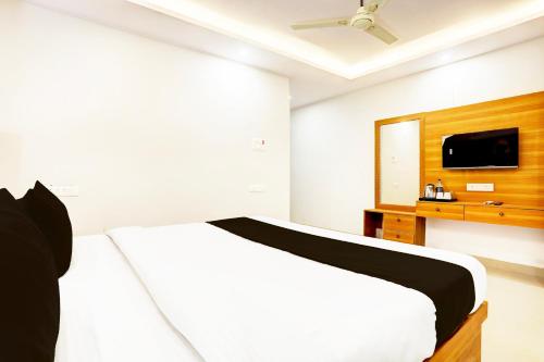 a white bedroom with a bed and a tv at Super Collection O Gola Road in Patna