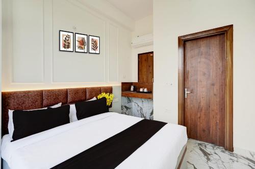 a bedroom with a large bed and a wooden door at Super Collection O Surajpur Chowk Greater Noida in Noida
