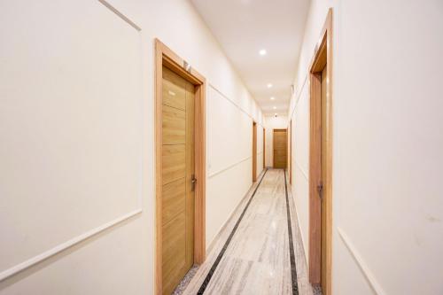 a hallway with a wooden door and white walls at Super Collection O Surajpur Chowk Greater Noida in Noida