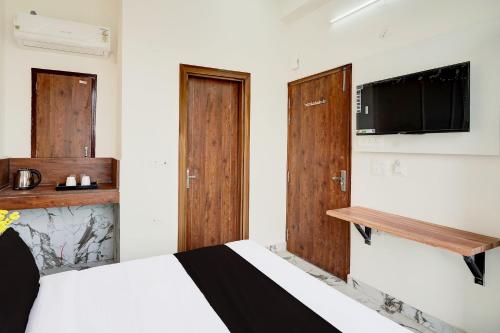 a bedroom with a bed with wooden doors and a tv at Super Collection O Surajpur Chowk Greater Noida in Noida