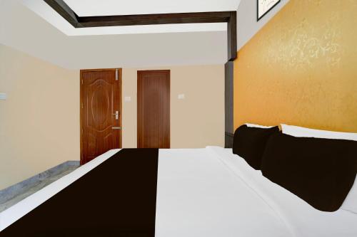 a bedroom with a white bed with black pillows at Super Hotel O Kazhakkoottam Near Technopark Phase 3 in Trivandrum