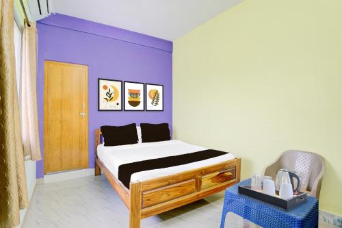 a bedroom with a bed and a purple wall at Hotel O Walajapeti Vellore in Wālājāpet