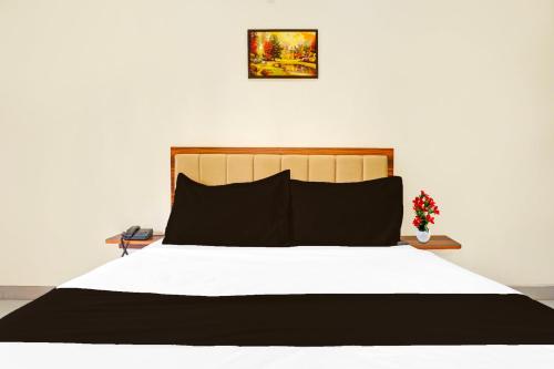 a bed with a black and white comforter at Super Townhouse Amanora Park Town Formerly Samrat Inn in Pune