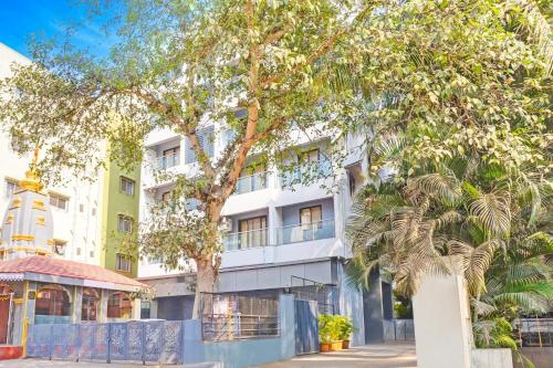 a white building with a tree in front of it at Super Townhouse Amanora Park Town Formerly Samrat Inn in Pune
