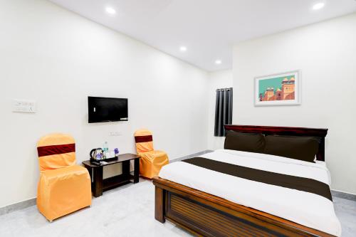 a bedroom with a bed and two chairs and a television at Super Collection O Vanasthalipuram in Hyderabad