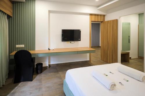 a room with a bed and a desk with a tv at Hotel Heraa Boarding Lodging in Mangalore
