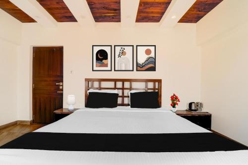 a bedroom with a bed and some pictures on the wall at Super Collection O Charing Cross Ooty in Ooty