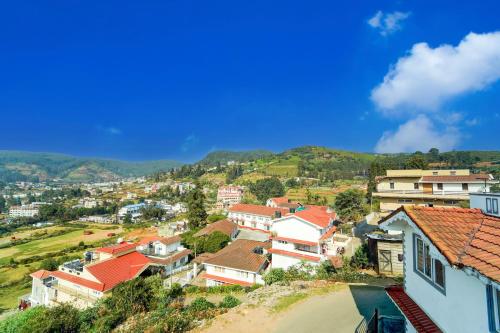 a village with houses and mountains in the background at Super Collection O Charing Cross Ooty in Ooty