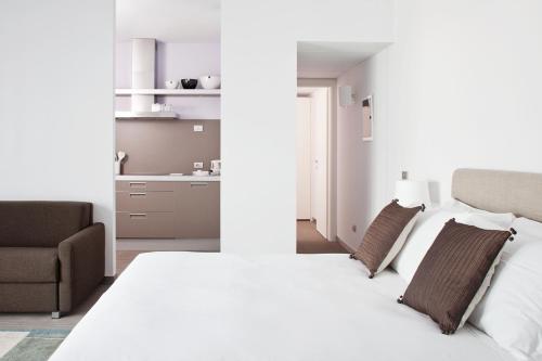 a white bedroom with a bed and a chair at Zambala Luxury Apartments in Milan