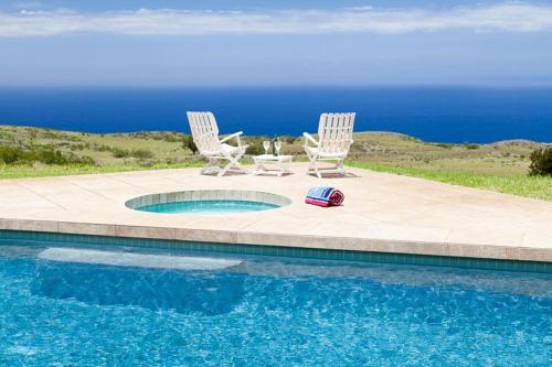 two chairs and a ball sitting next to a swimming pool at Mango Sunsets in Kawaihae