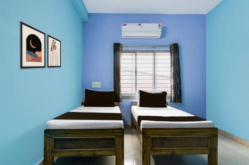two beds in a room with blue walls at Hotel O Durgapur Near NSHM College Formerly MON Palace in Mālandighi
