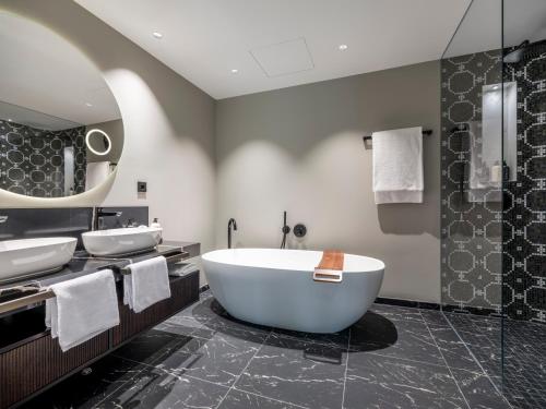 a bathroom with two sinks and a bath tub at Steigenberger Icon Europäischer Hof Baden Baden in Baden-Baden